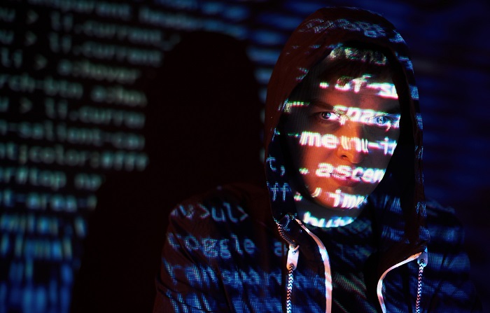 Cyber attack with unrecognizable hooded hacker using virtual reality, digital glitch effect